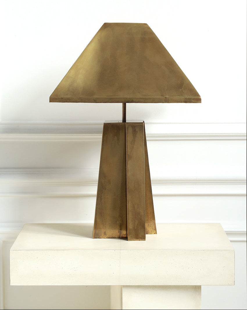 Brass table lamp on a white surface with a white wall background