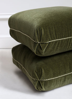 Two green cushions stacked on a white surface
