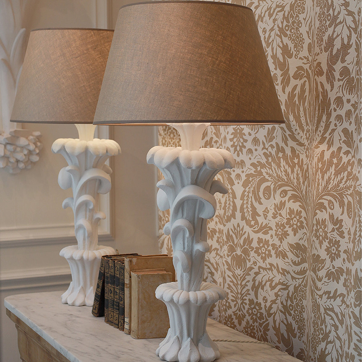 Decorative table lamps with intricate designs on a surface against a patterned wall.