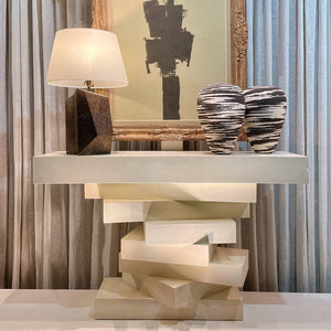 Modern console table with abstract art and decorative items in a room setting